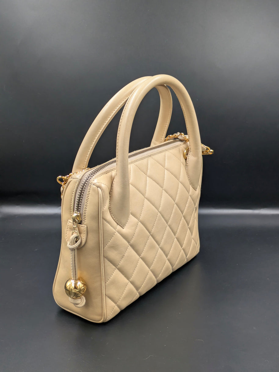 Sac Chanel vintage beige de trois quarts, anses rondes et zip à boule dorée