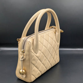 Sac Chanel vintage beige de trois quarts, anses rondes et zip à boule dorée