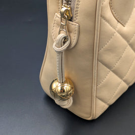 Zip du sac Chanel vintage beige terminé par une boule dorée, vue de côté