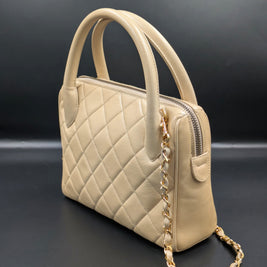 Sac Chanel vintage beige de profil avec chaîne dorée entrelacée de cuir