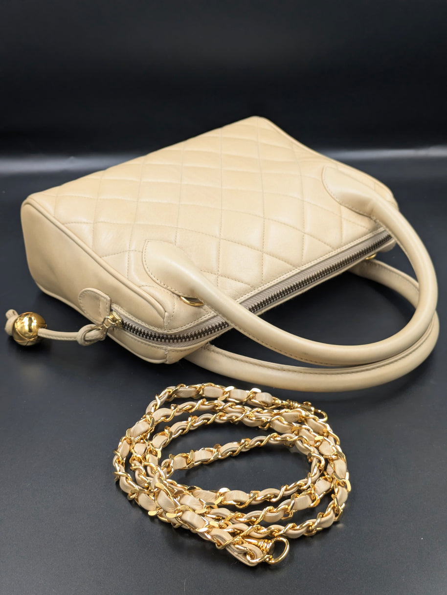Sac Chanel vintage beige posé avec sa bandoulière chaîne dorée déroulée