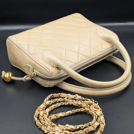 Sac Chanel vintage beige posé avec sa bandoulière chaîne dorée déroulée