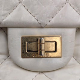 Gros plan sur le fermoir Mademoiselle doré gravé CHANEL du sac 2.55 écru