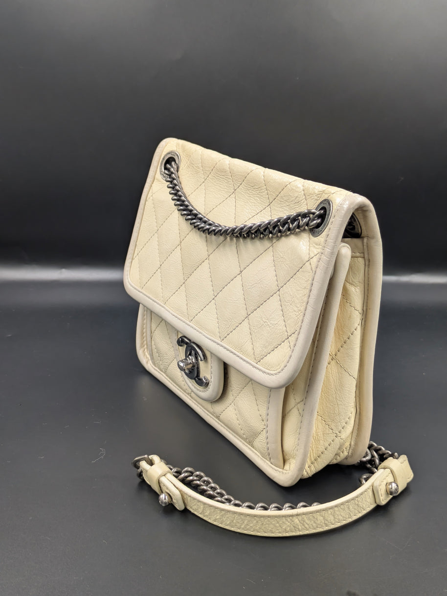 Chanel French Riviera Flap beige de profil, bandoulière chaîne et cuir
