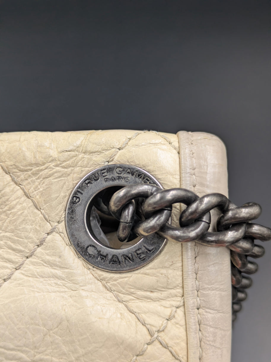 Gros plan sur l’œillet gravé CHANEL et la chaîne ruthénium du French Riviera Flap