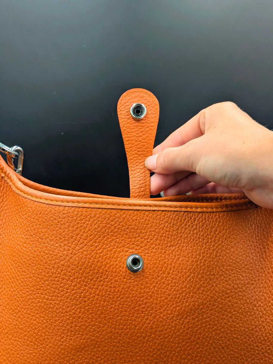 Hermès Evelyne PM cuir orange détail bouton pression