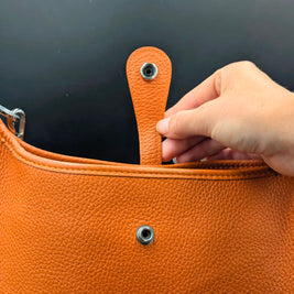 Hermès Evelyne PM cuir orange détail bouton pression